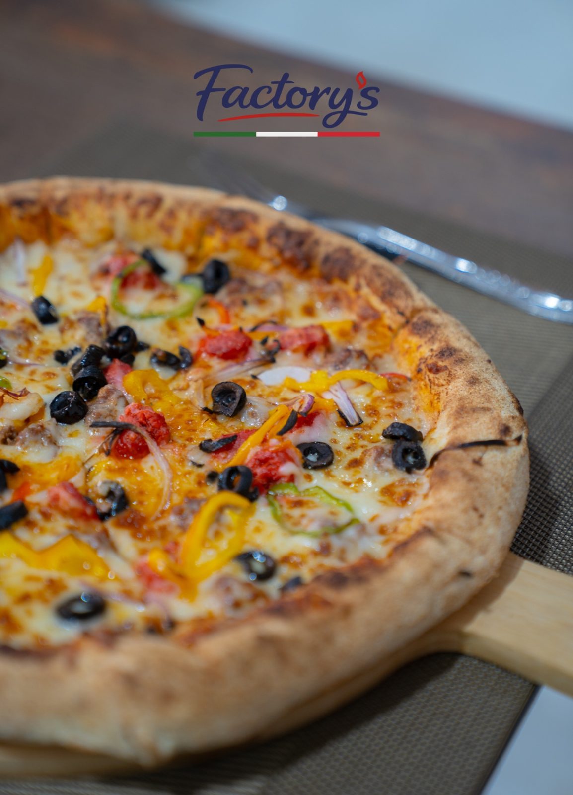 Gros plan sur une pizza garnie d'olives, poivrons et tomates