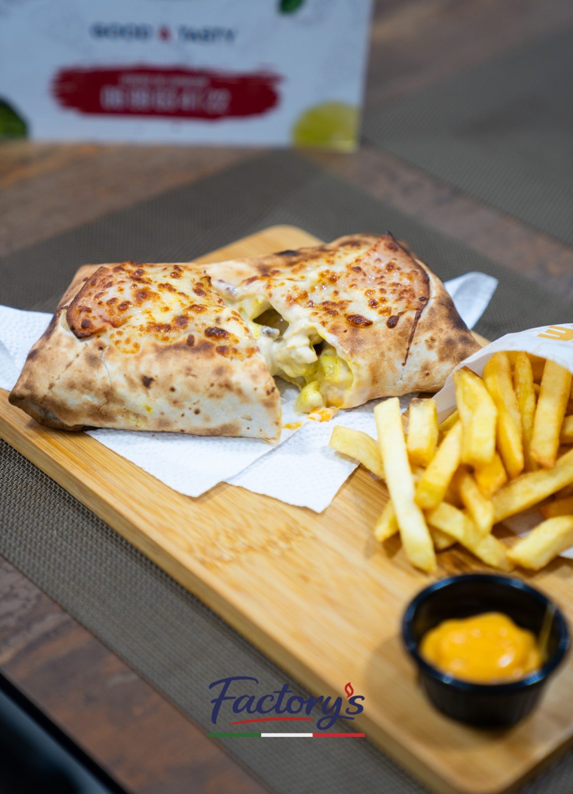 Calzone tranché sur plateau en bois avec frites et sauce