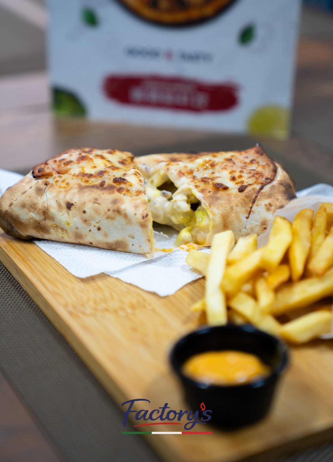 Calzone gratiné coupé en deux, servi avec des frites et une sauce