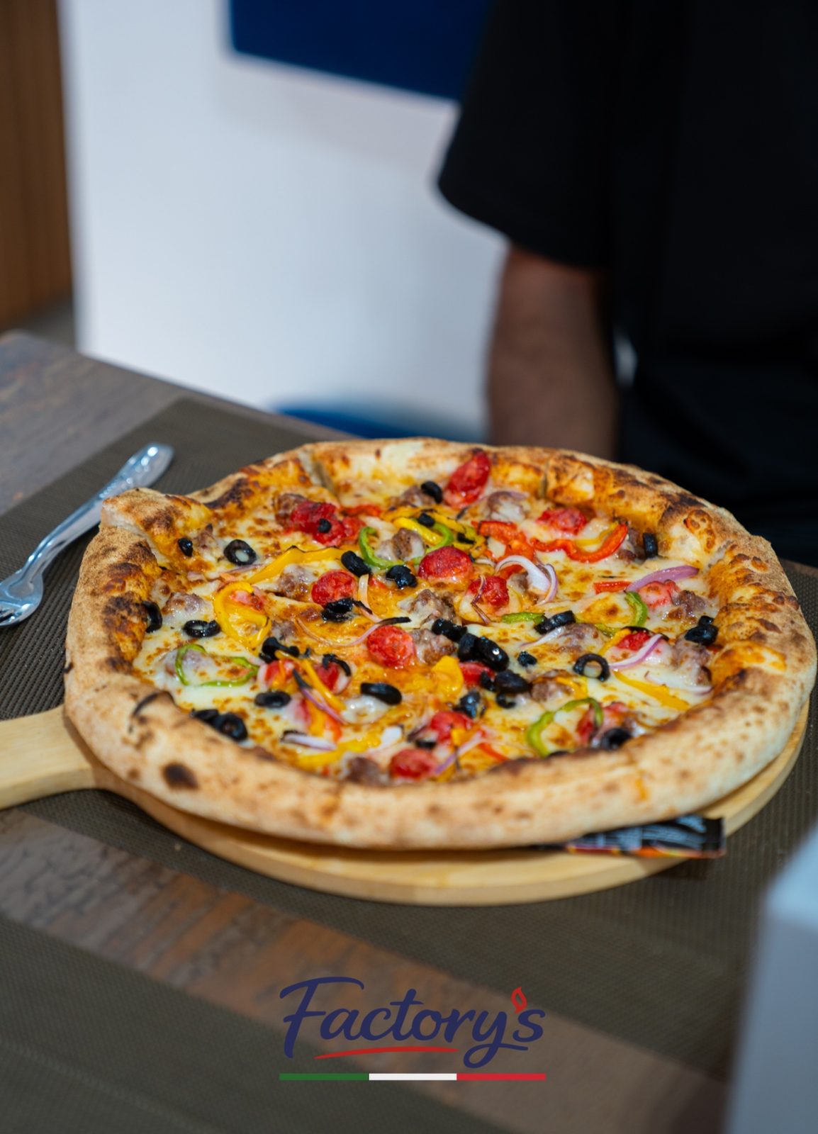 Pizza artisanale entière servie sur planche en bois chez Factory's